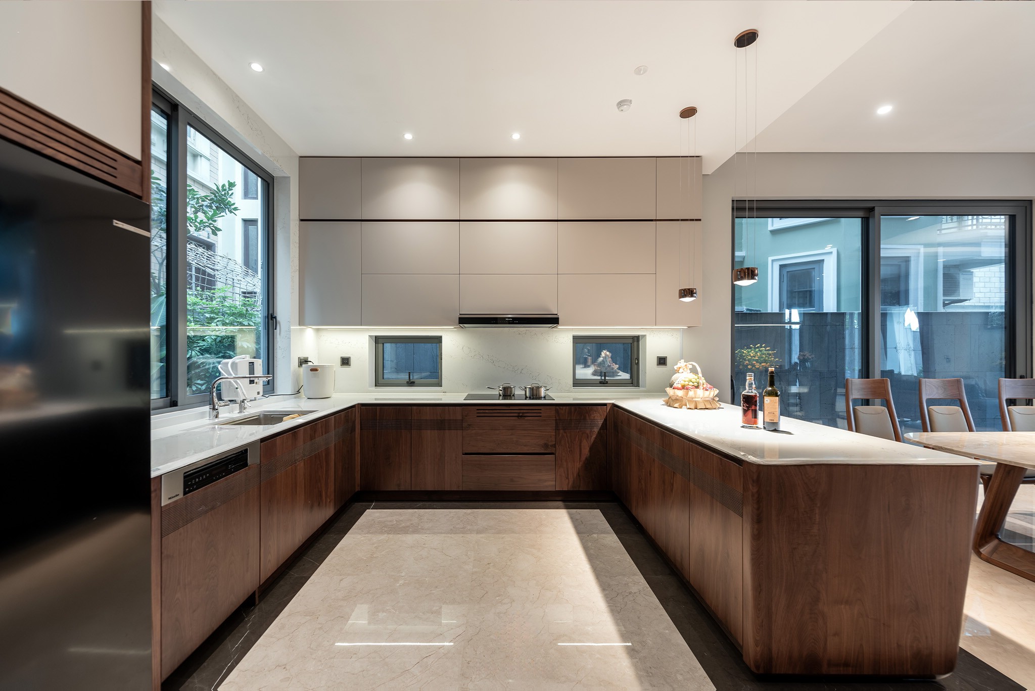 Tủ bếp đẹp hiện đại chữ L với veneer gỗ óc chó và bàn bar đá granite trắng